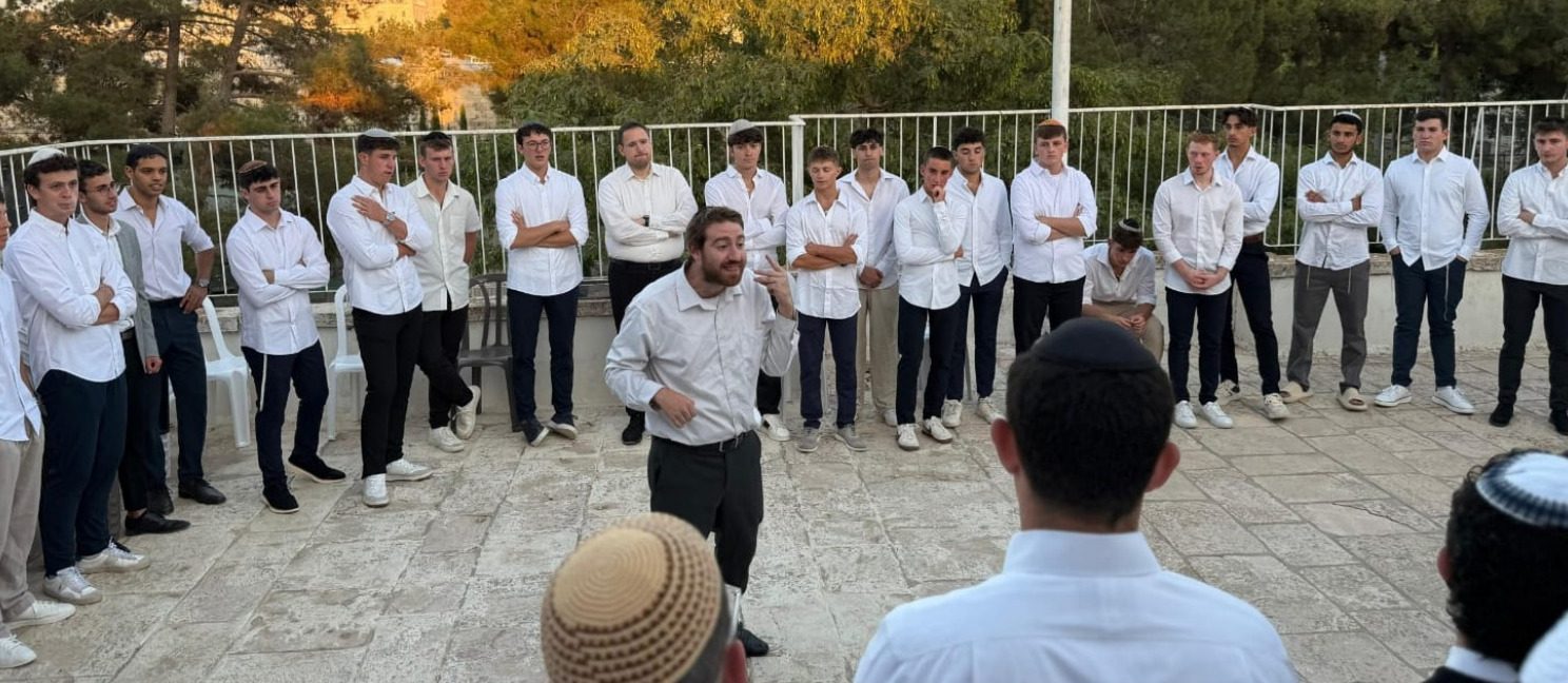 The yeshiva standing in a circle on campus on Shabbat, in white shirts