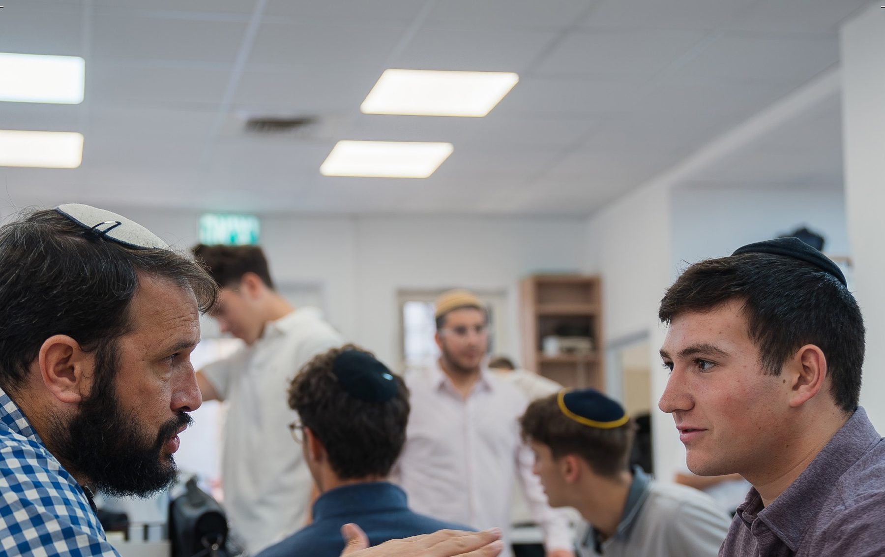 A Rebbe and a talmid learning across a table in the Beit Midrash